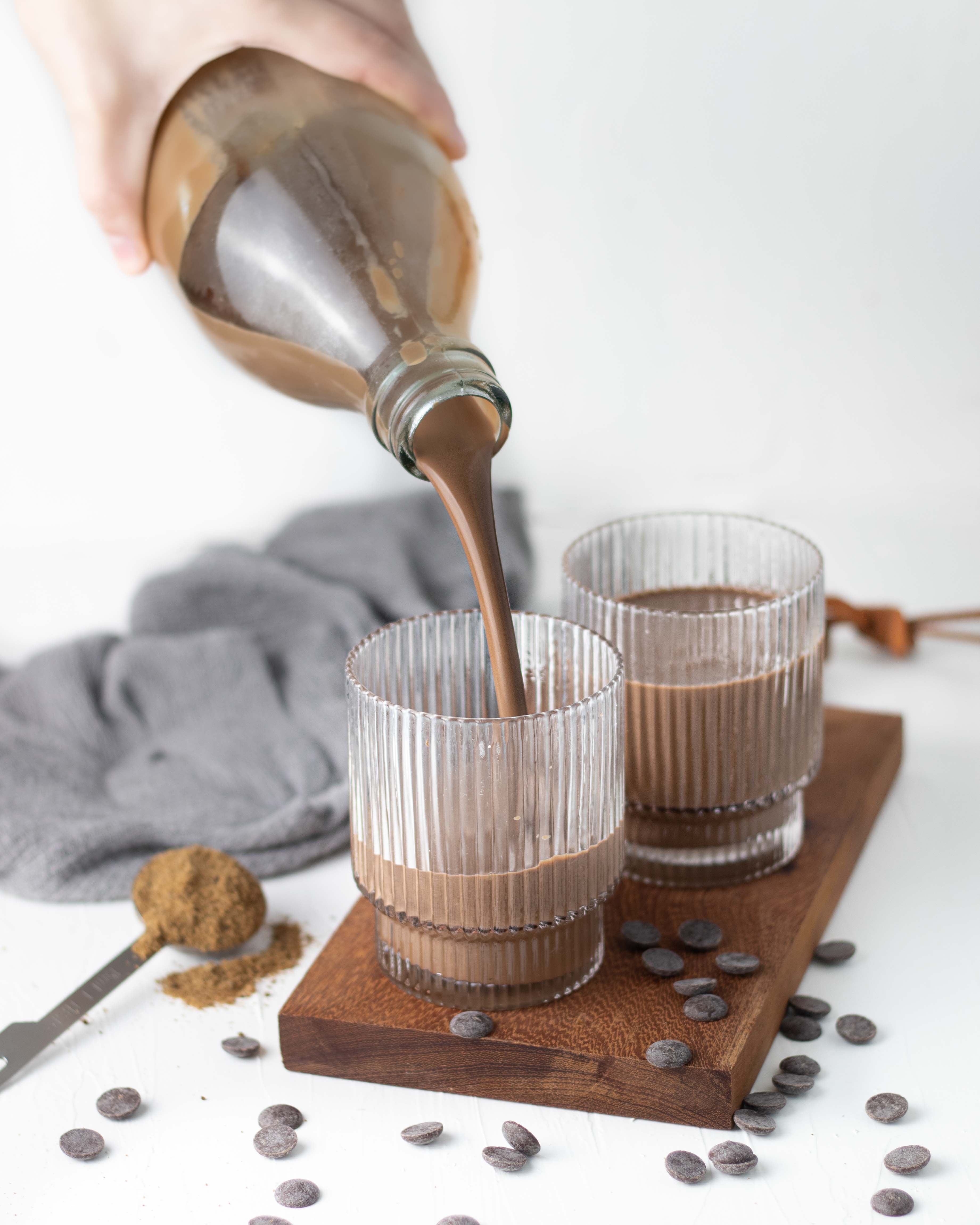 copo sendo preenchido com chocolate quente por uma mão segurando uma garrafa