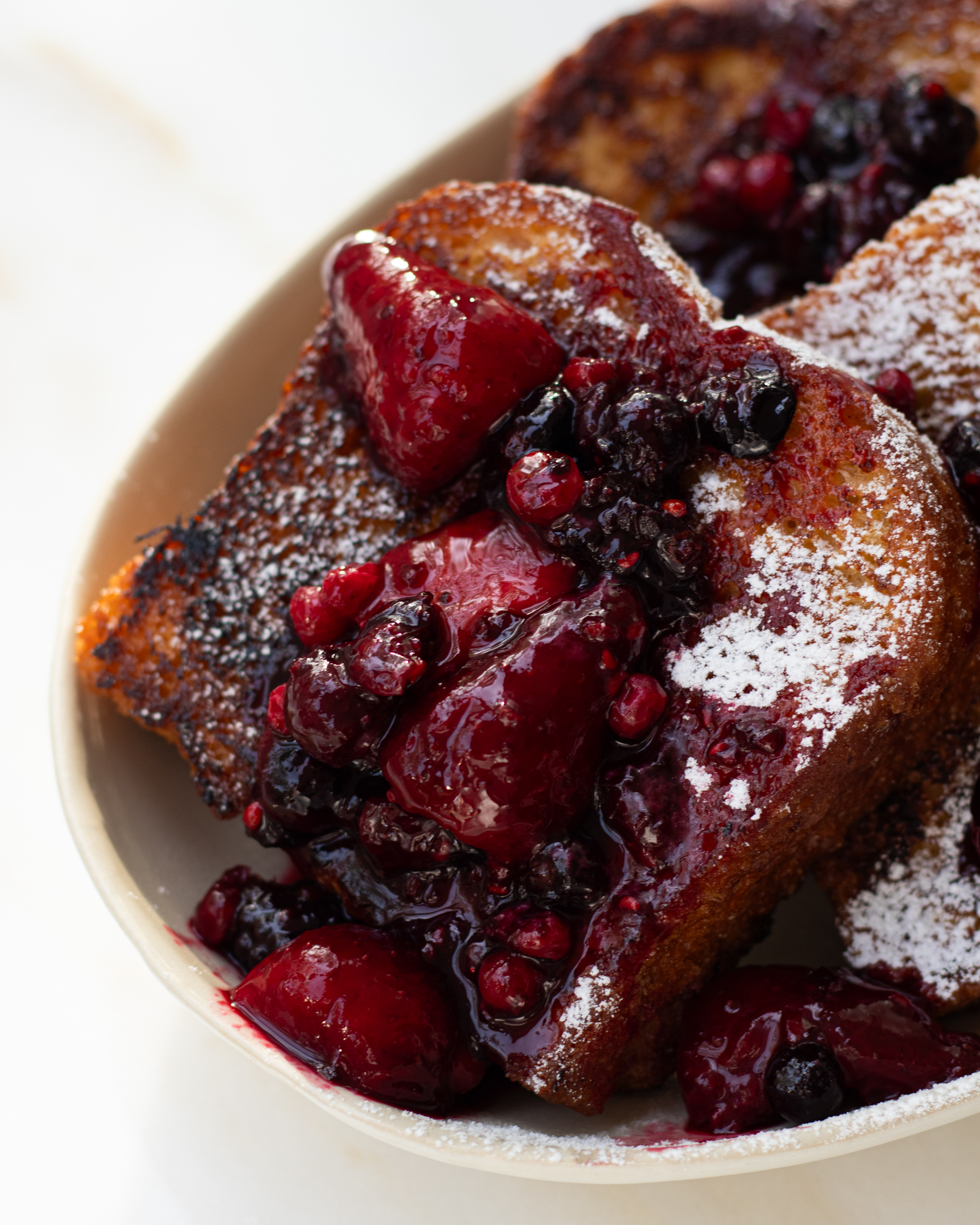 Delicious French toast on a plate with caramelized sugar topping and fresh berries.